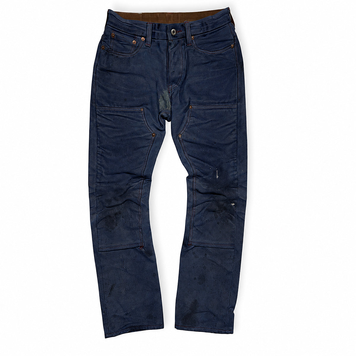 A pair of dark indigo blue denim work pants with reinforced patches and distressed details, laid flat against a white background.