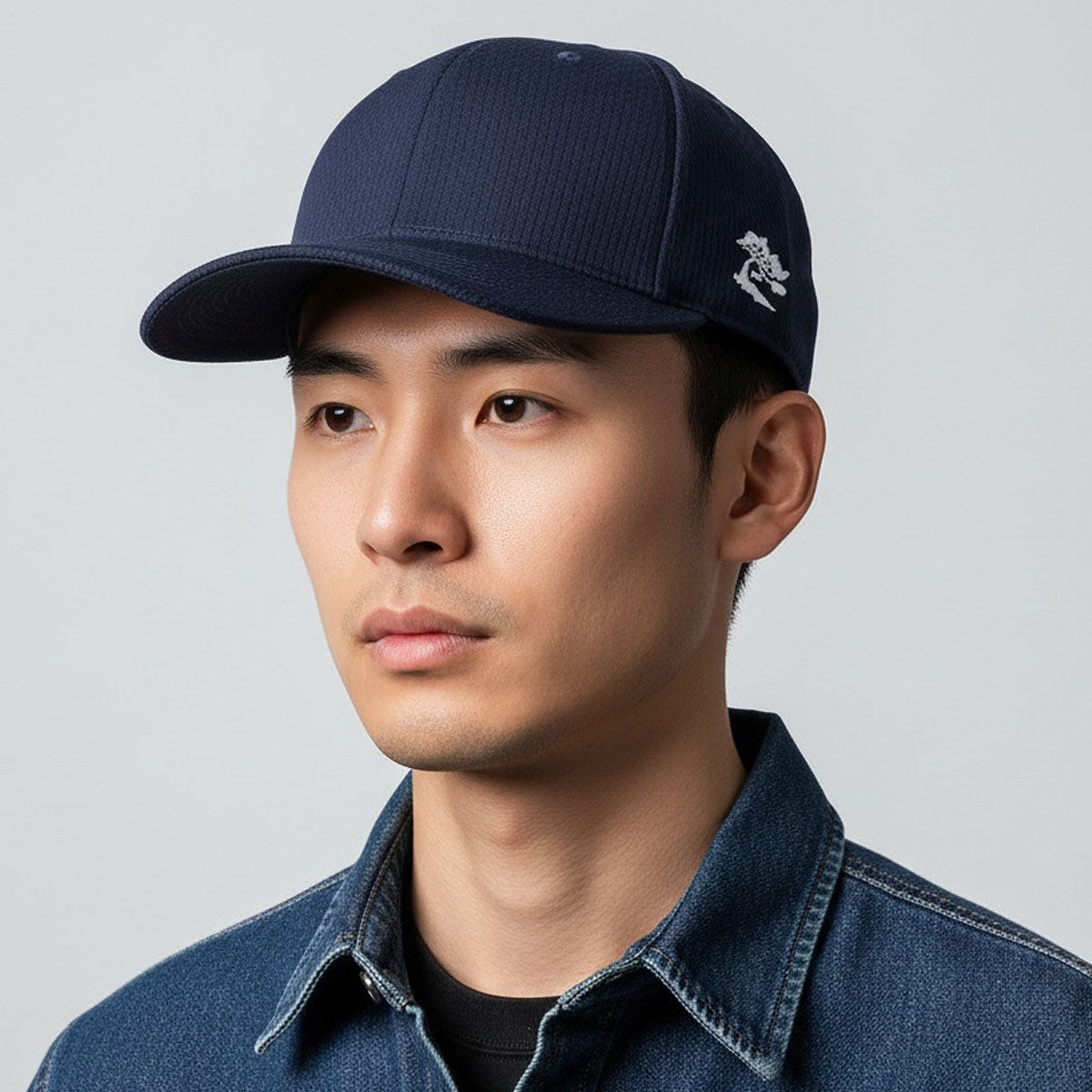 Man wearing a navy blue cap with a logo on a gray background