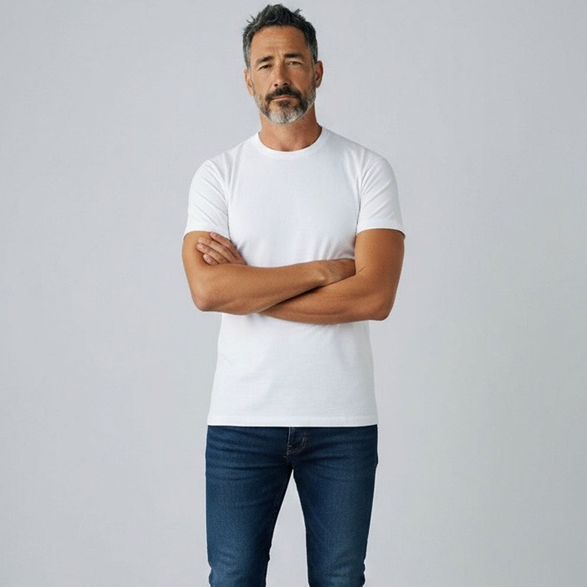 Man wearing a white t-shirt and blue jeans against a plain background